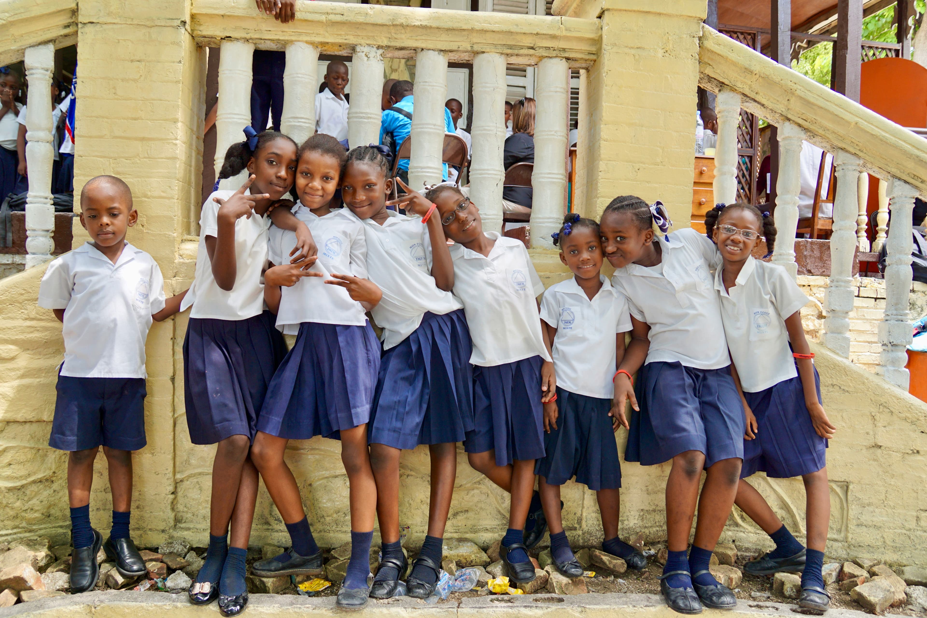 Students in school uniforms smiling together outside their school
